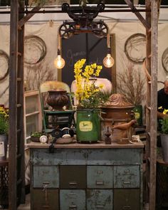 an outdoor market with lots of plants and flowers on it's display table,