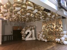 balloons and streamers hang from the ceiling in front of a large number twenty sign