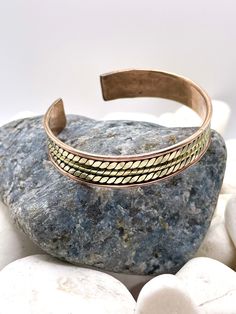 These bracelets are handmade in Nepal with pure coppers and brass.  Includes a jewellery polishing cloth.  Size: 18cm  Width: 10mm  As It's open-ended, would fit most hands To fit the bracelet open it up so the gap is wide enough to pass over the narrowest part of your wrist and then squeeze it back into shape until it is a nice comfortable fit. Please note due to this item being handmade there may be some imperfection.  Wearing pure copper jewellery can turn your skin green due to chemical reac Handmade Gold Braided Brass Bracelets, Handmade Adjustable Traditional Gold Bracelet, Traditional Adjustable Copper Cuff Bracelet, Traditional Adjustable Rose Gold Bracelets, Traditional Handmade Adjustable Gold Bracelet, Handmade Traditional Gold Bracelet, Adjustable Copper Bangle, Traditional Style, Adjustable Traditional Copper Bangle, Adjustable Brass Artisan Bracelets