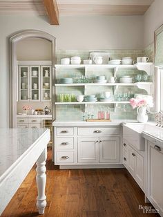 a kitchen filled with lots of white cabinets and counter top next to a wooden floor