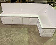 a white bench that is sitting in the middle of a room with some drawers on it