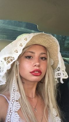 a woman wearing a white hat in the back seat of a car with long blonde hair