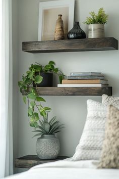 two wooden shelves with plants and books on them in a bedroom area next to a bed