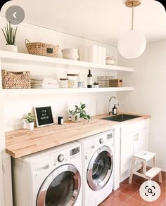 a washer and dryer in a small room with white cupboards on the wall