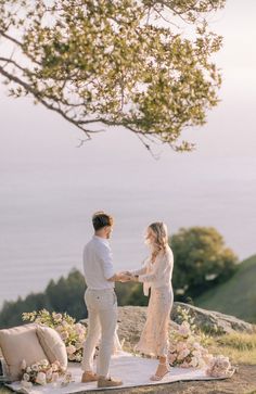 a man and woman standing on top of a hill