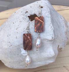 "I have to say these are one of my favorites. The rectangle is cut out of copper sheet metal, heated, folded and hammered. The folds make the cross. Heating up the metal creates the unique patina. Dangling from the bottom of the rectangle is a white freshwater pearl bead. The rectangle measures approx. 3/4\" high by a little over 1/4\"wide. Your earrings will be slightly different from the picture but that's what makes them so unique and a one- of -a kind! Earrings wires are surgical  A gift bag Rust Dangle Earrings With Ear Wire, Rust Color Dangle Earrings With Ear Wire, Soldered Copper Earrings As A Gift, Handmade Rust Earrings For Gift, Bronze Pearl Drop Earrings For Gift, Brown Pearl Drop Earrings As Gift, Brown Pearl Drop Earrings For Gift, Turquoise Bead Earrings, White Pearl Jewelry