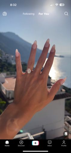 someone holding their hand up in front of the camera with an ocean view behind them