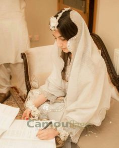 a woman sitting on top of a white couch next to a table filled with papers