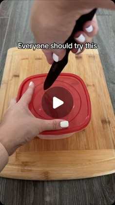 someone is cutting something with a knife on top of a wooden board that says everyone should try this