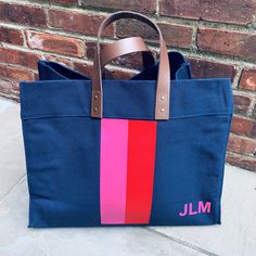 Our best-selling leather handle canvas tote, now with stripes! Another great option for a housewarming, wedding, or graduation gift. Or just nab one for yourself and carry it to work in style. Coordinates with our wide stripe zip top! 14"h x 18"w x 8.25"d. Leather handles with 5" drop. Open top with two inside pockets. Ivory: 20oz canvas. Colors: 18oz canvas. Vinyl stripes and lettering.Need help with color or style options? Give us a call! Navy Bag, Vinyl Monogram, Wide Stripes, Monogram Styles, Custom Monogram, Garden Tote, Vinyl Colors, Leather Handles, Open Top