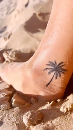 a small palm tree tattoo is on the foot of a person's feet at the beach