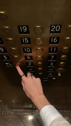 a person pointing at the numbers on an elevator door with their finger in the air