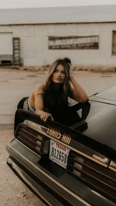 a woman leaning on the hood of a car