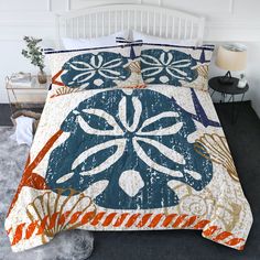 a bed with an orange, blue and white comforter on it in a bedroom