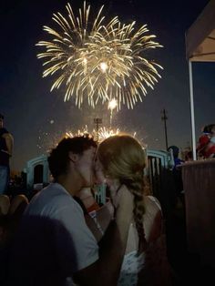 a man and woman kissing in front of fireworks