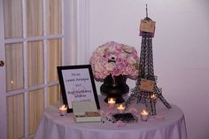 a table with flowers and candles on it in front of the eiffel tower