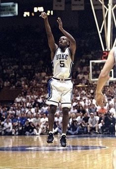 a basketball player jumping up to dunk the ball in front of an audience at a game