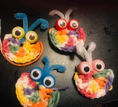 three crocheted bugs sitting on top of a black table next to each other