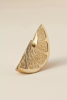 a gold ring with an intricate design on the front and back side, sitting on a white surface