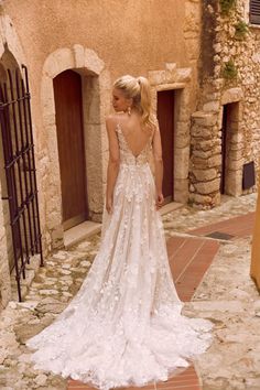 a woman in a wedding dress is walking down the street with her back to the camera