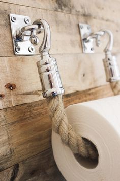 a roll of toilet paper hanging on a wooden wall next to two rolls of rope