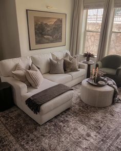 a living room filled with furniture and a large painting on the wall above it's windows