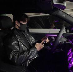 a man wearing a face mask while sitting in a car looking at his cell phone