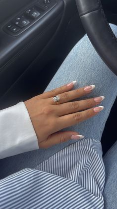 a woman's hand on the steering wheel of a car with her nails painted white