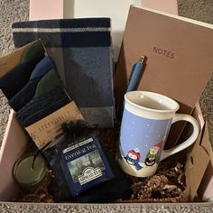 an open box with coffee, tea and other items in it on the carpeted floor