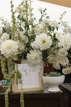 a vase filled with white flowers sitting on top of a table next to a sign