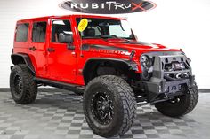 a red jeep is parked in front of a sign that says rubit tru