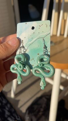 a pair of green earrings sitting on top of a white table next to a chair