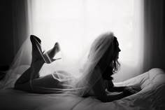 a woman laying on top of a bed under a veil