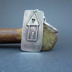 a metal keychain with a house and heart on it sitting next to a rock