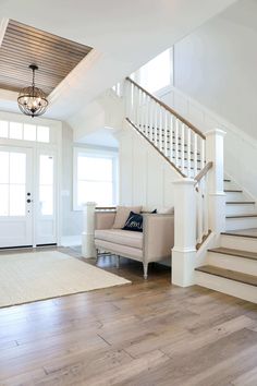 a living room filled with furniture and a stair case next to a door on top of a hard wood floor