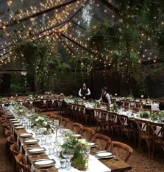 an outdoor tent with tables and chairs set up for a formal dinner under string lights