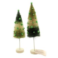 two small trees with green lights on top of each one and a white stand holding a card