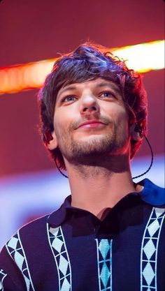 a man with ear buds on his ears looking up at the sky while wearing a sweater