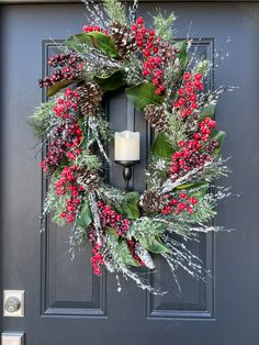 a christmas wreath is hung on the front door with a lit candle and evergreens