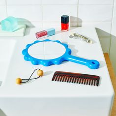 a blue comb sitting on top of a white counter next to a mirror and other items