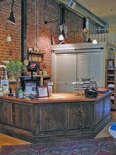 a large wooden counter sitting inside of a room next to a brick wall with lights on it