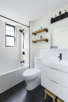 a white toilet sitting next to a bath tub in a bathroom with black tile on the floor