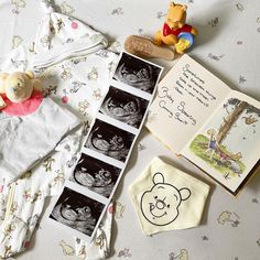 winnie the pooh baby book, teddy bear and other items laid out on a bed