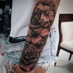 a woman's arm with black and white tattoos on it, including roses and butterflies