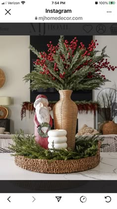 a vase with red berries in it sitting on top of a table next to a santa clause