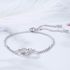 A brilliant way to show her your love is forever, this dainty bracelet will certainly touch her heart. This meaningful design showcases two ribbons interlocked for a infinity symbol-shaped look, while shimmering round stones add eye-catching sparkle to the design. This elegant bracelet makes a stunning statement of everlasting love. A great anytime choice, this fashion bracelet is sure to become an instant favorite. Carat Weight: 0.21 ctStone Size: 1.1 mmNumber of Stones: 21 Stone Shape: RoundSt Elegant Infinity Bracelets With Diamond Accents, Elegant Infinity Bracelet With Diamond Accents, Elegant Cubic Zirconia Bracelets For Mother's Day, Elegant Infinity Bracelets For Mother's Day, Elegant Infinity Bracelet For Mother's Day, Elegant Infinity Diamond Bracelet In White Gold, Elegant Infinity Cubic Zirconia Jewelry, Elegant Infinity Bracelets For Wedding, Elegant Wedding Infinity Bracelets