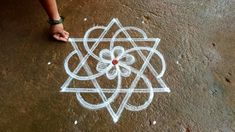 a person standing on top of a sidewalk next to a white chalk drawing in the shape of a flower