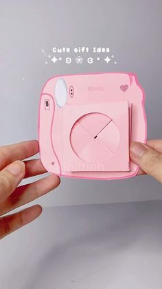 someone is holding up a pink camera shaped like a clock with hello kitty stickers on it