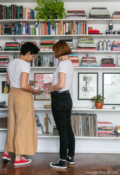 two women standing in front of a bookshelf