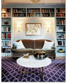 a living room filled with furniture and lots of bookshelves on the wall behind it